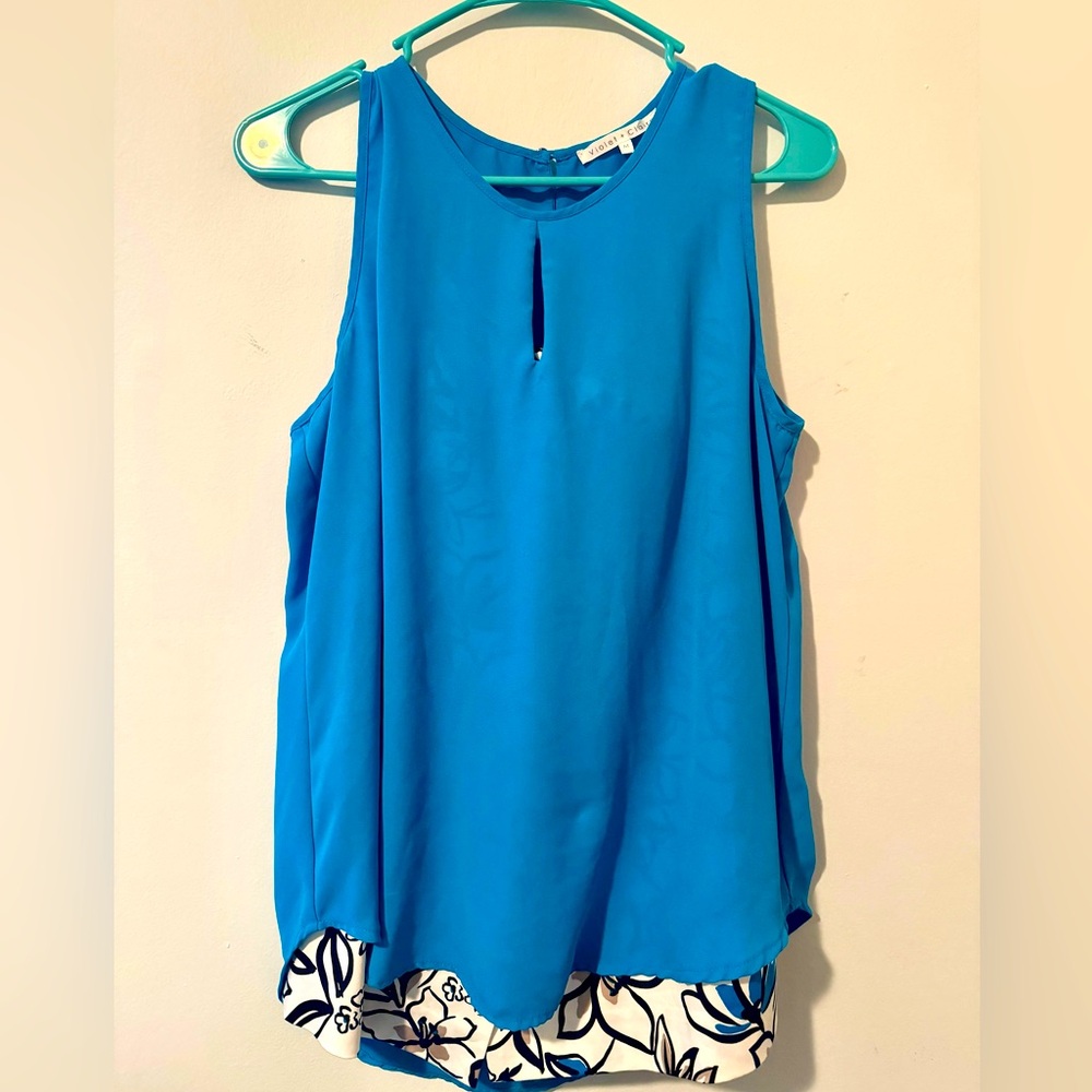 Teal blouse with teal and black highlights on a white skirt.